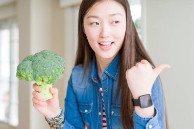 İşaret ve başparmak kadar mutlu yüz gülümseyen tarafı ile gösterilen yeşil taze brokoli yemek güzel Asyalı kadın