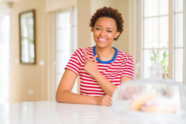 Genç güzel Afrikalı-Amerikalı kadın ve neşeli bir gülümseme yüzünü elimle işaret ile ev yan yüzünde mutlu ve doğal ifade ile kadar parmak