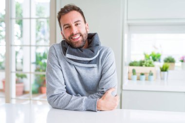 Yakışıklı adam giyen sıradan kazak evde ve gülümseyen varsaymak