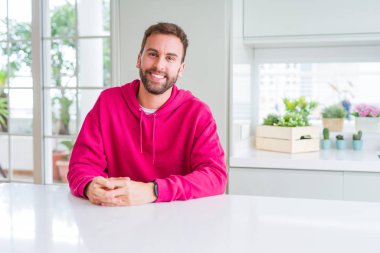 Yakışıklı adam giyen sıradan kazak evde ve gülümseyen varsaymak