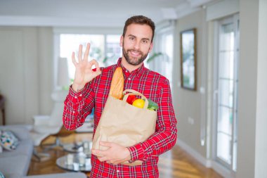 Yakışıklı adam yiyecek ihale parmak, mükemmel sembolü ile ok işareti yapıyor