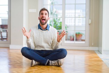 Yakışıklı adam evde çılgın ve kızgın bağırarak ve agresif ifade ve silah kaldırdı bağırmaya katta oturan rahat kazak giyiyor. Hayal kırıklığı kavramı.