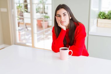 Güzel genç kadın bir fincan sade kahve düşünme seyir içme yorgun ve sıkılmış çapraz silah depresyon sorunları ile.