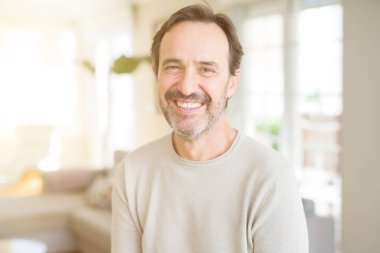 Evde kameraya bakarak gülümseyen yakışıklı orta yaş erkek