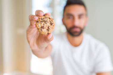 Yakışıklı İspanyol adam yeme çikolata Çerezler kendine güvenen bir ifade ile acımak yüz ciddi düşünüyorum cips