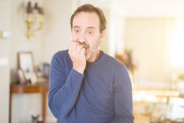 Yakışıklı orta yaş erkek evde stresli ve gergin elle çivi ısırma ağzına bakıyor. Anksiyete sorunu.
