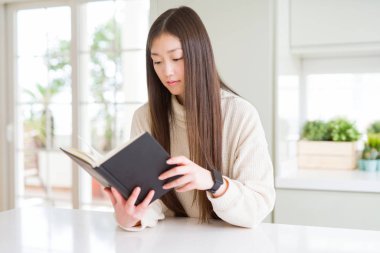 Güzel Asyalı kadın kendinden emin bir ifade ile acımak yüz ciddi düşünme bir kitap okuma