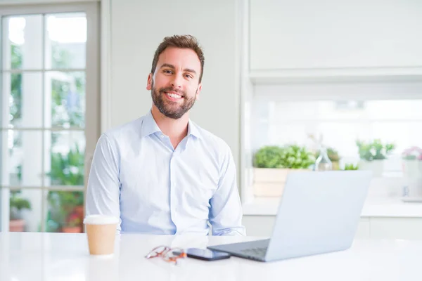 Hombre de negocios guapo trabajando con computadora portátil y sonriendo —  Fotos de Stock