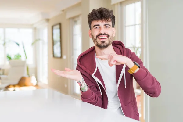 Jonge Man Dragen Casual Sweatshirt Zittend Witte Tafel Verbaasd Lachend — Stockfoto