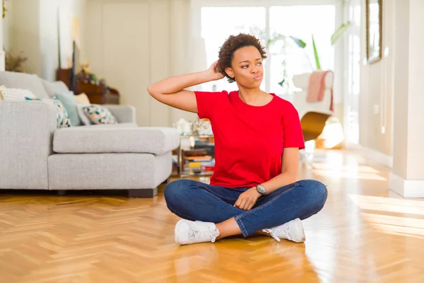 年轻美丽的非洲裔美国妇女坐在家里的地板上混淆和疑惑的问题 不确定与怀疑 用手在头上思考 沉思的概念 — 图库照片
