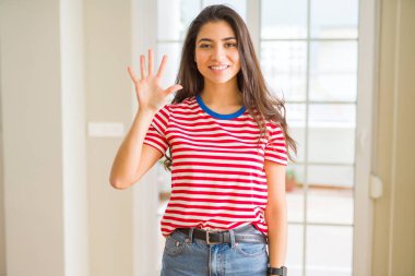 Gösterilen ve parmakları ile işaret rahat t-shirt giyen genç güzel kadın kendinden emin ve mutlu gülümseyerek süre beş numara.