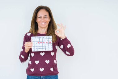 Adet takvim parmak, mükemmel sembolü ile ok işareti yapıyor izole arka plan üzerinde tutan orta yaş kadın