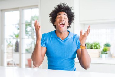 Afrika kökenli Amerikalı adam evde deli ve çığlık kaldırdı ve kapalı gözleri heyecanlı silah ile başarı için deli kutluyor. Kazanan kavramı