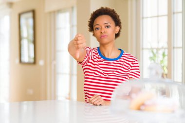 Genç güzel Afrikalı-Amerikalı kadın evde mutsuz ve kızgın ret gösterilen ve başparmak aşağı hareketi ile negatif arıyorum. Kötü ifade.