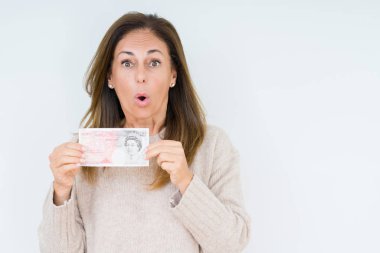 50 pound banknot izole arka plan üzerinde bir sürpriz yüz, korkuyor ve heyecanlı korku ifadesi ile şok korkmuş tutan orta yaş kadın