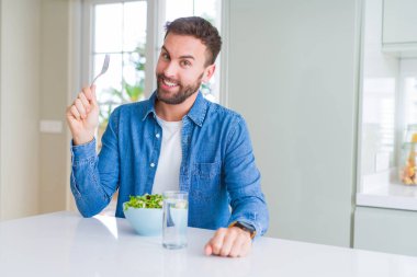 Yakışıklı adam evde yeşil bezelye yeme