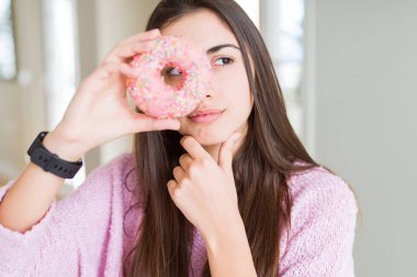 Pembe çikolata parçaları çörek ciddi bir yüz düşünme hakkında soru, çok karışık fikir yemek güzel genç kadın