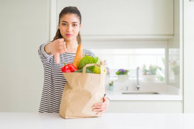 Kağıt torba yiyecek kızgın yüzü, eksi işareti aşağı antipati başparmak ile gösterilen, ret kavramı ile tam tutan genç kadın