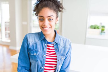 Yüzünde mutlu ve güzel bir gülümseme ile rahat denim ceket giyen afro saçlı güzel genç Afro-Amerikan kadın. Şanslı kişi.