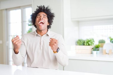 Gülümseyen ve başarı için çığlık Afro-Amerikan bir adam evde çok mutlu ve heyecanlı kaldırdı, silah ile kazanan jest yapıyor. Kutlama kavramı.