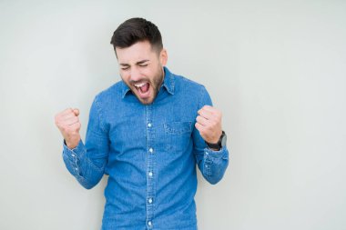 Soyutlanmış, mutlu ve heyecanlı genç bir adam kollarını kaldırmış, gülümseyen ve başarı için çığlık atan kazanan bir jest yapıyor. Kutlama konsepti.