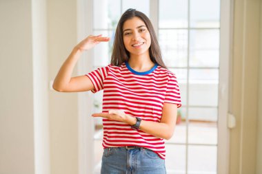Büyük ve büyük boy işaret, ölçü birimi sembol gösteren elleriyle işaret rahat t-shirt giyen genç güzel kadın. Kameraya bakarak gülümsüyordu. Ölçüm kavramı.