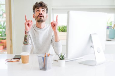 Genç adam bilgisayar kullanarak çalışma hayret ve yukarıya bakıp parmakları ile işaret şaşırttı ve silah kaldırdı.