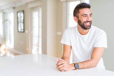 Yakışıklı İspanyol casual beyaz t-shirt ev uzak tarafına gülümseme ile yüzünde, doğal ifade arıyorum, dostum. Kendine güvenen gülüyor.