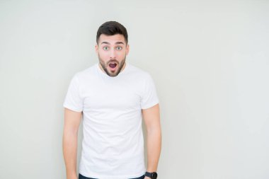İzole arka plan korkuyor ve şok sürpriz ifade, korku ve heyecan yüz üzerinden Casual beyaz t-shirt giyen genç yakışıklı adam.