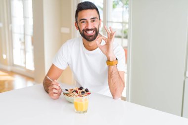 Ok işareti parmaklar, mükemmel sembolü ile İspanyol yakışıklı sabahları sağlıklı kahvaltı evde yemek yapıyor