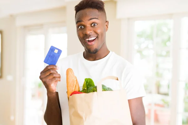 Hombre Afroamericano Sosteniendo Bolsa Papel Llena Comestibles Con Tarjeta Crédito — Foto de Stock
