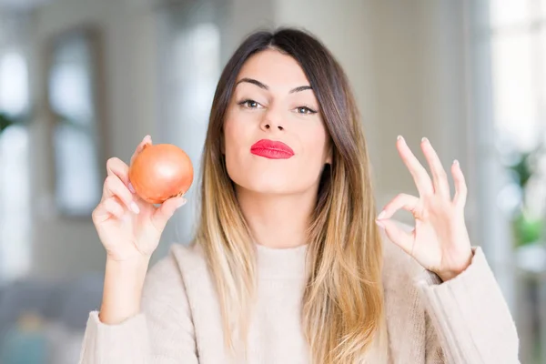 Joven Hermosa Mujer Sosteniendo Cebolla Fresca Casa Haciendo Signo Con — Foto de Stock