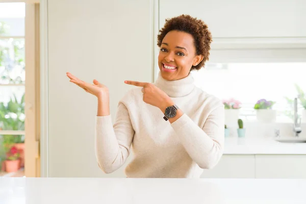年轻美丽的非洲裔美国女人在家里惊讶和微笑的镜头 而呈现与手和手指指指点点 — 图库照片