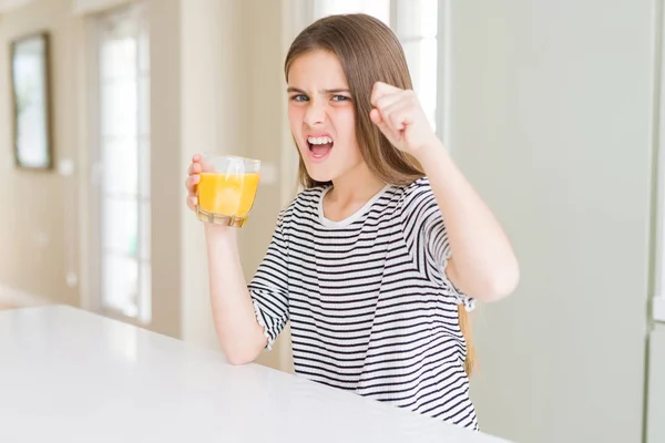 美しい若い女の子子供飲んで腹の新鮮なオレンジ ジュースのガラスと狂気と怒り概念の上げられた手で叫んで 怒りと不満の叫び — ストック写真