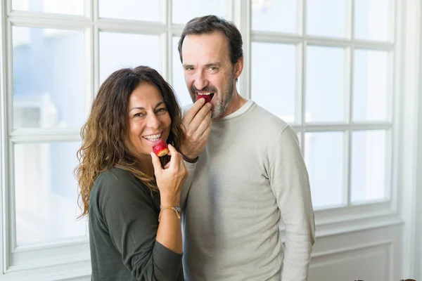 Middle age senior couple eating a fresh strawberry at home