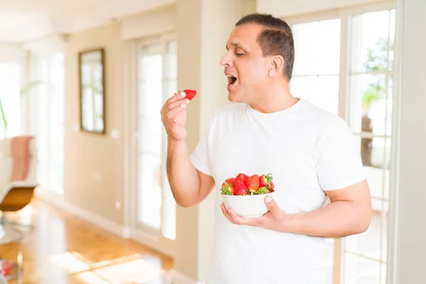 Midaldrende Mand Spiser Jordbær Derhjemme - Stock-foto