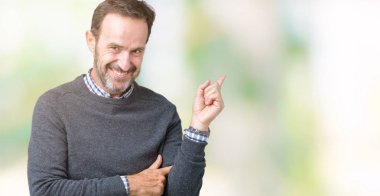 Kameraya bakarak yan el ve parmak ile işaret yüzünde kocaman bir gülümseme ile izole arka plan üzerinde bir Kazak giymiş yakışıklı orta yaş komuta sizde.