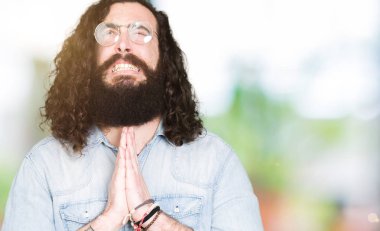 Uzun saç ve sakal yalvarıyor ve umut ifade yüzünde çok duygusal ve endişe ile birlikte elleriyle dua gözlüklü genç hipster adam. Bağışlanmak. Din kavramı.