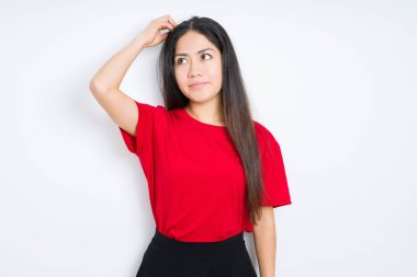İzole arka plan üzerinde kırmızı t-shirt giyen güzel esmer kadın yanıltır ve soru hakkında merak ediyorum. Şüphe, kafasına el ile düşünme ile belirsiz. Dalgın kavramı.