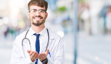 Genç doktor adam giyen hastane kat izole üzerinden alma veya jest vererek birlikte el avuç içi ile gülen arka plan. Ayrı tutma ve koruma