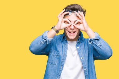 Genç yakışıklı adam, dilini parmaklarının arasından baktığını yapışmasını dürbün gibi ok jest yapıyor izole arka plan üzerinde güneş gözlüğü takıyor. Deli ifade.