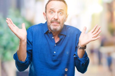 Orta yaş izole arka plan clueless ve şaşkın bir ifadeyle kollar ve eller kaldırdı üzerinde ağarmış komuta sizde. Şüphe kavramı.