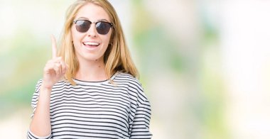 Güzel genç kadın ile başarılı fikir izole arka plan işaret parmağı üzerinde güneş gözlüğü takıyor. Çıktıktan ve mutlu. Bir numara.