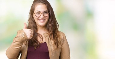 Güzel artı boyutu genç kadın hareketi el ile mutlu yaşasın yapıyor izole arka plan üzerinde elbise ve deri ceket giyiyor. Kameraya bakarak başarı gösteren ile ifade onaylama.