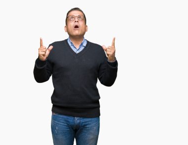 Orta yaş bussines Arap adam izole arka plan üzerinde gözlük hayret ve yukarıya bakıp parmakları ile işaret şaşırttı ve silah kaldırdı.