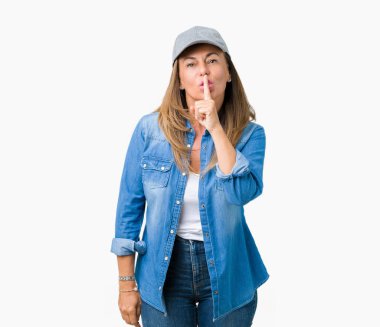 Dudaklarında parmak ile sessiz olmanı izole arka plan üzerinde spor şapkası giyen güzel orta yaş kadın. Sessizlik ve gizli kavramı.