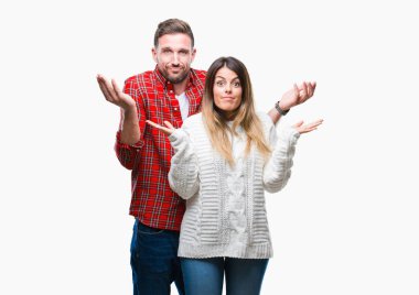 Young couple in love wearing winter sweater over isolated background clueless and confused expression with arms and hands raised. Doubt concept. clipart