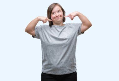 Genç Yetişkin kadın kendinden emin gösterilen ve işaret parmakları diş ve ağız ile gülümseyen izole arka plan üzerinde down sendromlu. Sağlık kavramı.