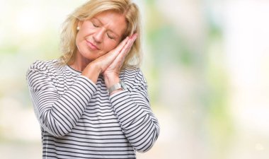 Orta yaş uyku yorgun hayal ve ellerle birlikte poz ile kapalı gözler gülümseyen izole arka plan sarışın kadın.