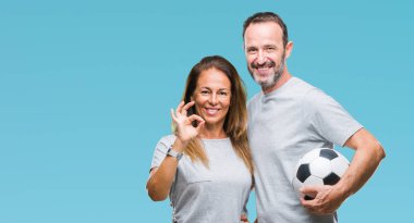 Orta yaş İspanyol çift parmak, mükemmel sembolü ile ok işareti yapıyor izole arka plan üzerinde futbol futbol topu tutan